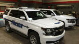 Cortland Police vehicle graphics installation on two white Chevy SUVs in a garage environment.