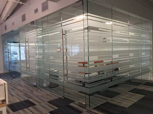 Frosted vinyl graphics on glass conference room partitions in an office setting with modern flooring.