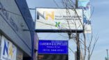 Illuminated storefront sign for Near North Health Razem Health Center with supporting banner above.