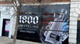 Large-format wall graphic featuring 1800 Cristalino Añejo Tequila, with an illustration of the bottle and splash effects.
