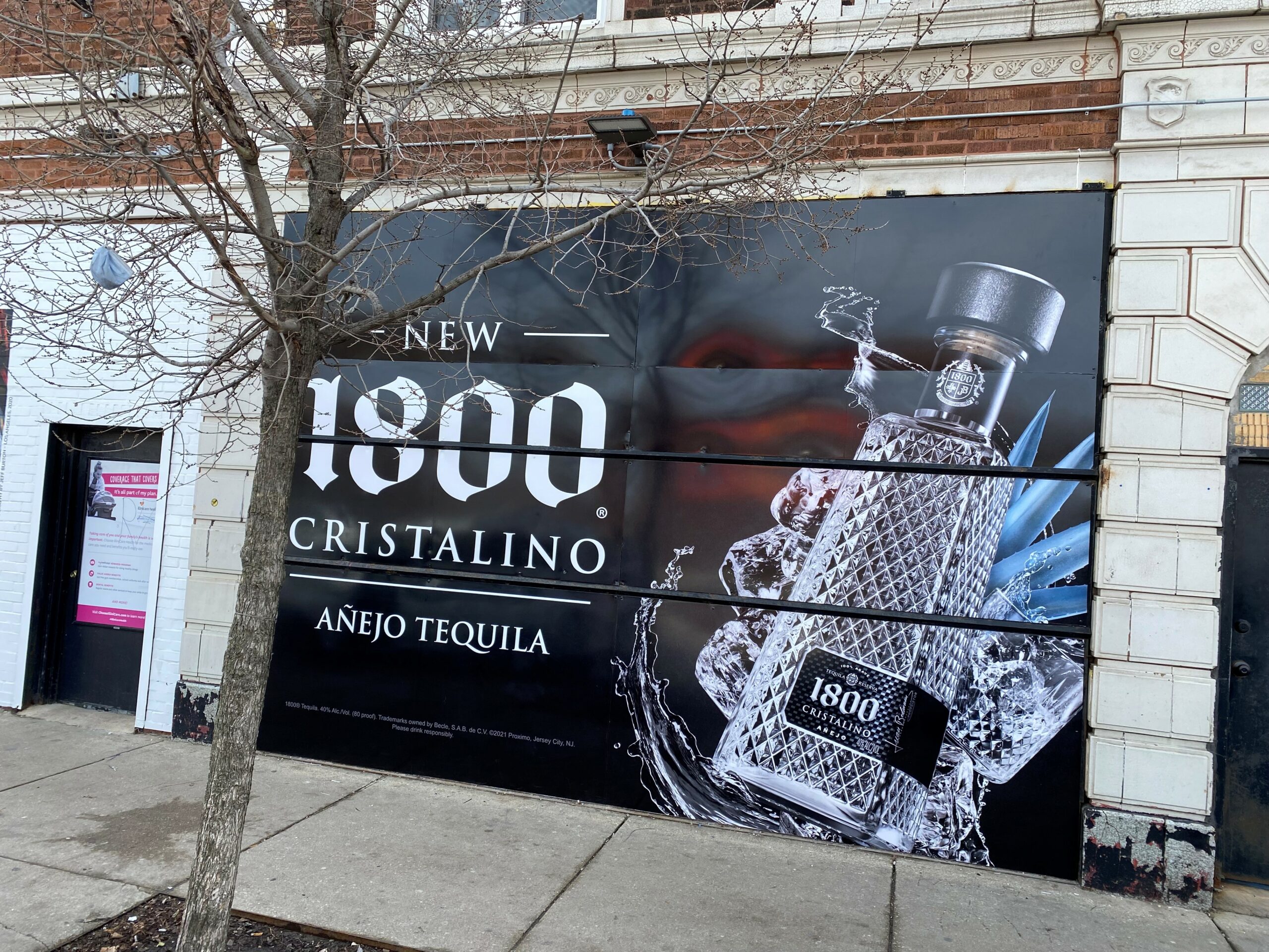 Large-format wall graphic featuring 1800 Cristalino Añejo Tequila, with an illustration of the bottle and splash effects.