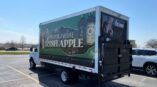 Full truck wrap featuring Proper Twelve Irish Apple branding and imagery of beer bottles in a parking lot.