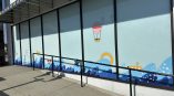 Environmental graphics featuring a whimsical ocean scene on storefront windows, including submarines, sailboats, and waves.