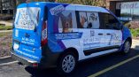 Partial vehicle wrap for The Dog Wizard featuring dog images and contact information on a blue and white van.