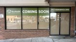 Window graphic for Numark Credit Union announcing 'Coming Soon' on a green background, visible on storefront glass.