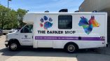 Full vehicle wrap for The Barker Shop featuring colorful dog graphics and contact information on a mobile grooming van.