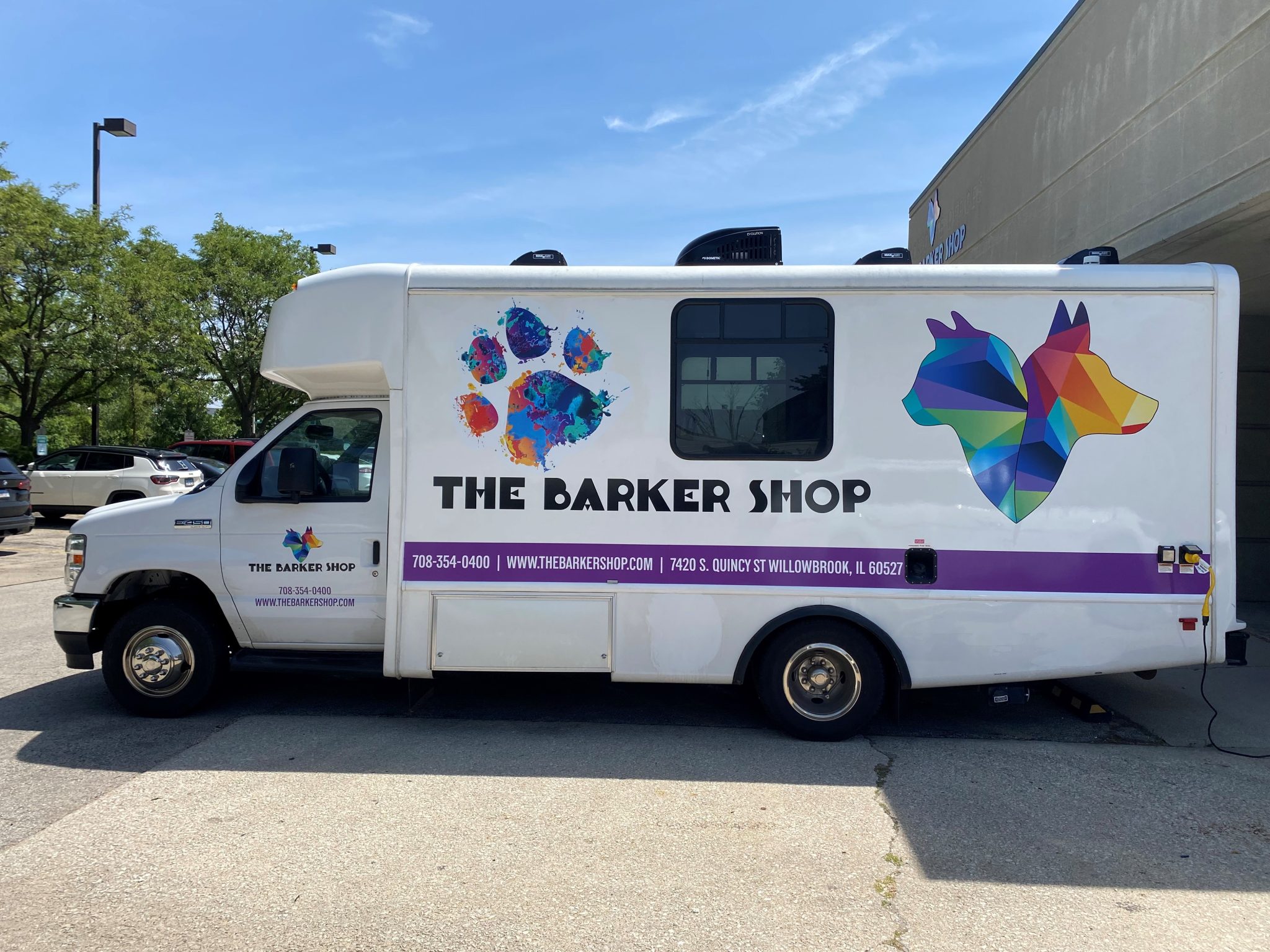 Full vehicle wrap for The Barker Shop featuring colorful dog graphics and contact information on a mobile grooming van.