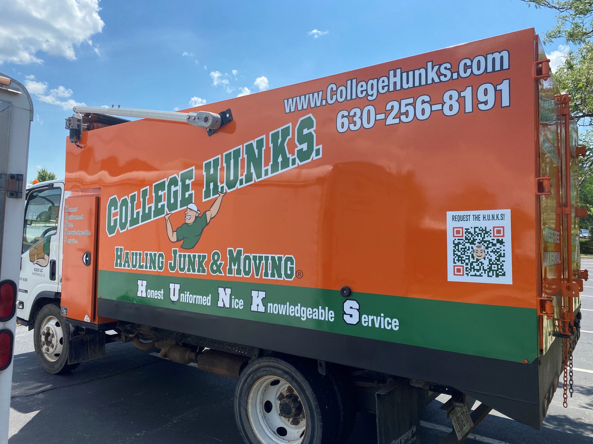 Full truck wrap for College Hunks featuring orange and green graphics with contact information and a QR code.