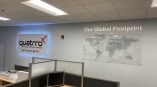 Illuminated channel letters for Quattro Business Support Services with an acrylic world map display in the office.