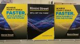 Retractable banners for Rimini Street featuring a yellow and blue design with IT goals messaging.