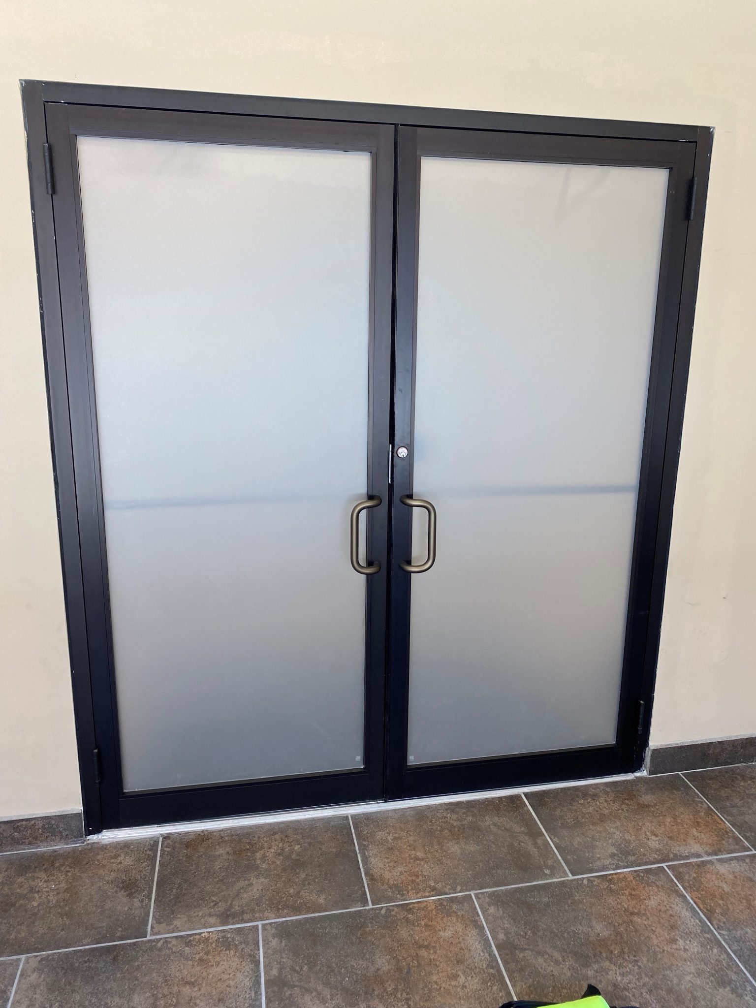 Frosted vinyl graphics installed on double glass doors with black frames and bronze handles.