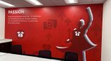 Wall mural in a conference room featuring red background, inspirational text, and a silhouette of a figure with arms raised.