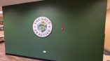 Dimensional wall sign for The Golf Practice featuring a circular logo on a green-painted wall.