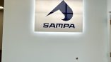 Illuminated acrylic sign displaying the SAMPA logo mounted on a light blue wall.