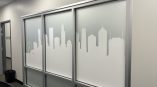 Frosted vinyl graphics featuring a Chicago skyline silhouette on office partition panels.