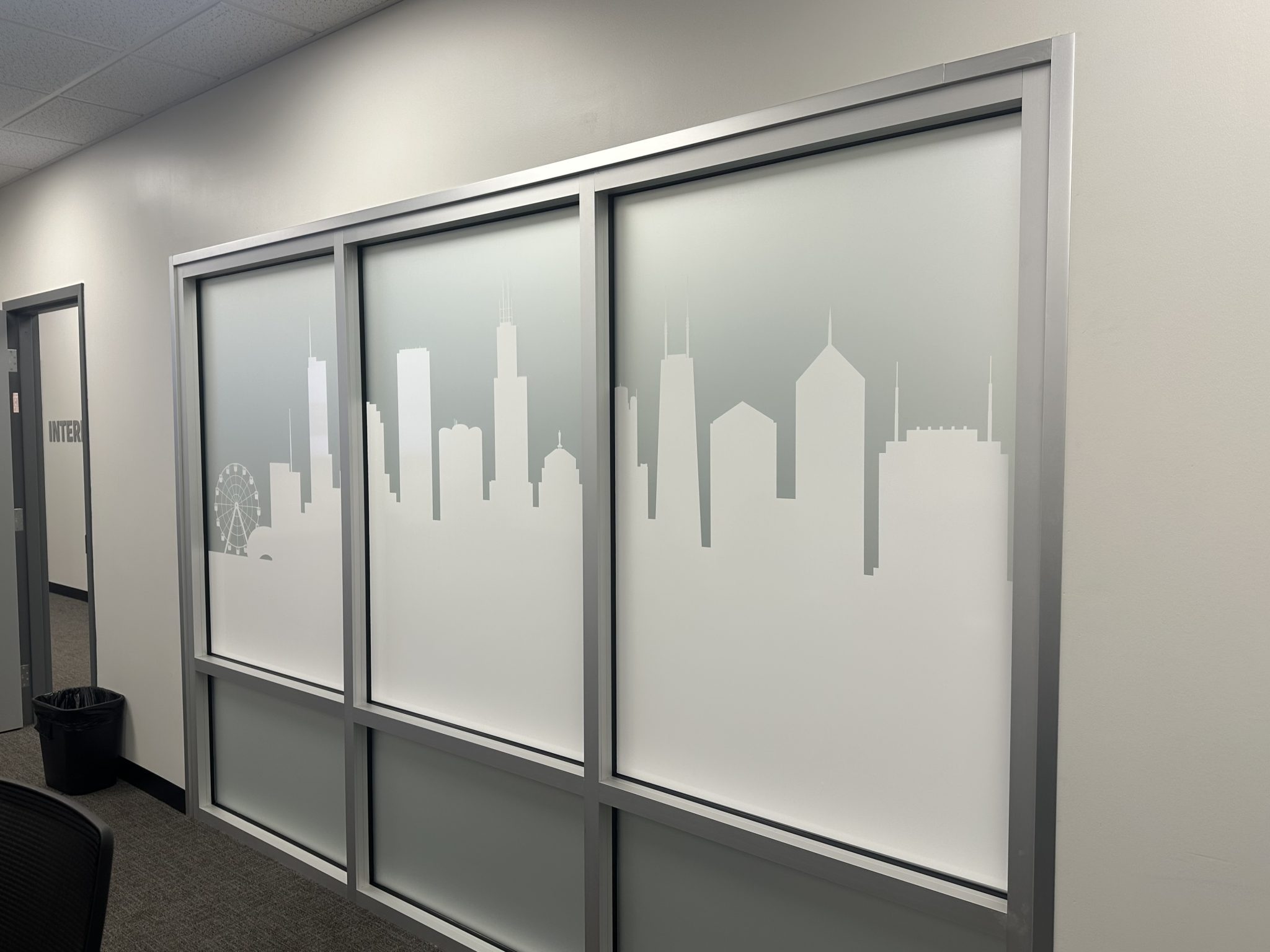 Frosted vinyl graphics featuring a Chicago skyline silhouette on office partition panels.