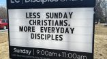 Directional signage for Disciples Church displaying text: 'Less Sunday Christians. More Everyday Disciples' with service times.
