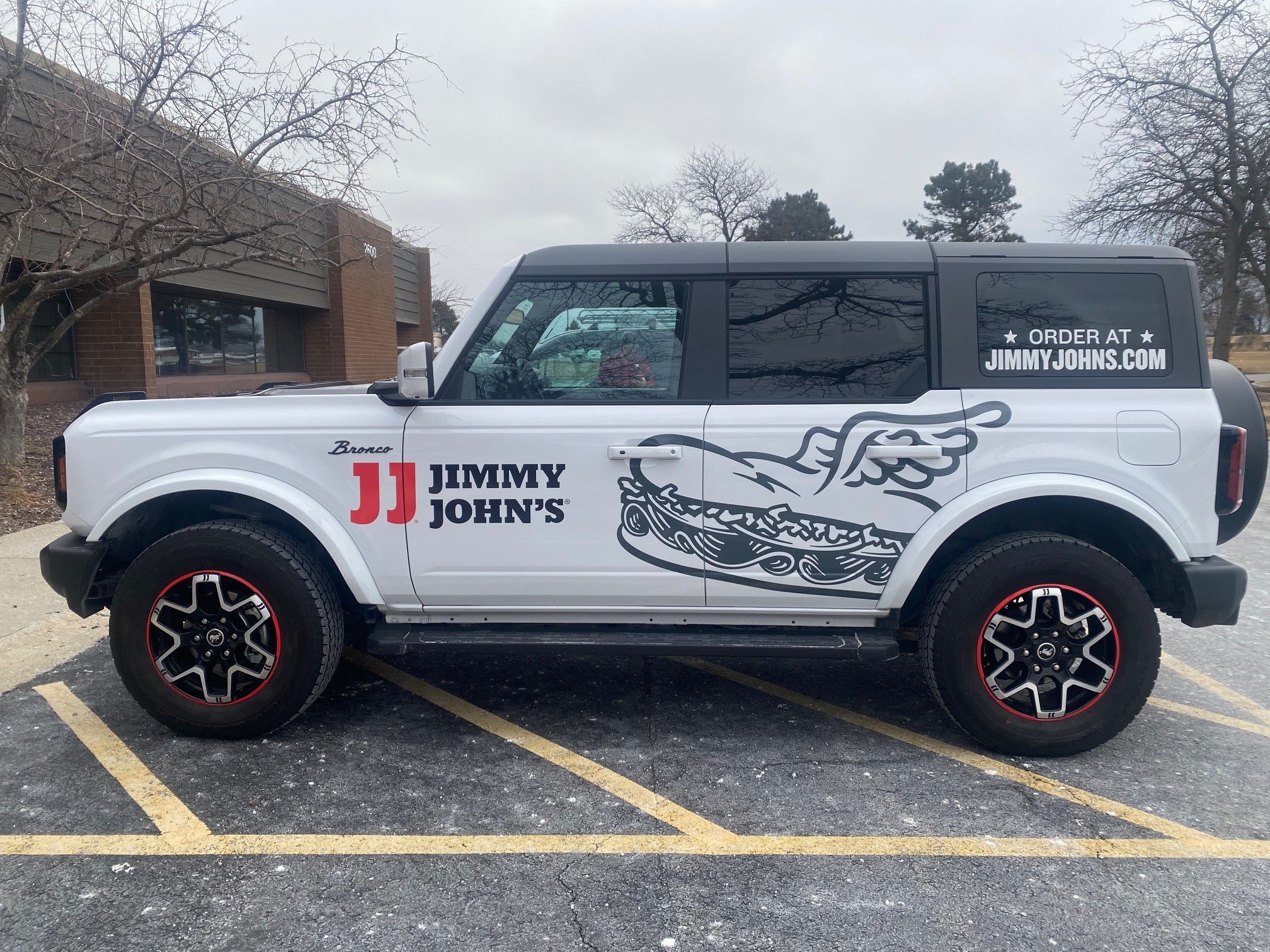 Partial vehicle wrap on a white Ford Bronco for Jimmy John's featuring red accents and sandwich graphics.