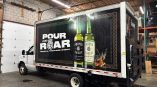 Full truck wrap for Proper No. Twelve Irish Whiskey featuring bold graphics and vibrant imagery inside a warehouse environment.