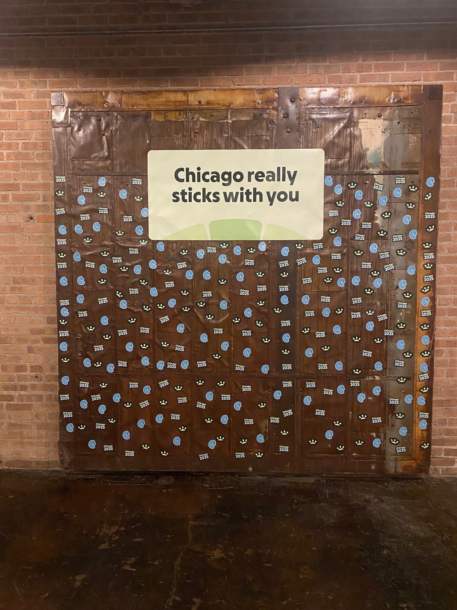 Wooden wall covered with blue and black stickers, featuring the phrase 'Chicago really sticks with you' in large text.