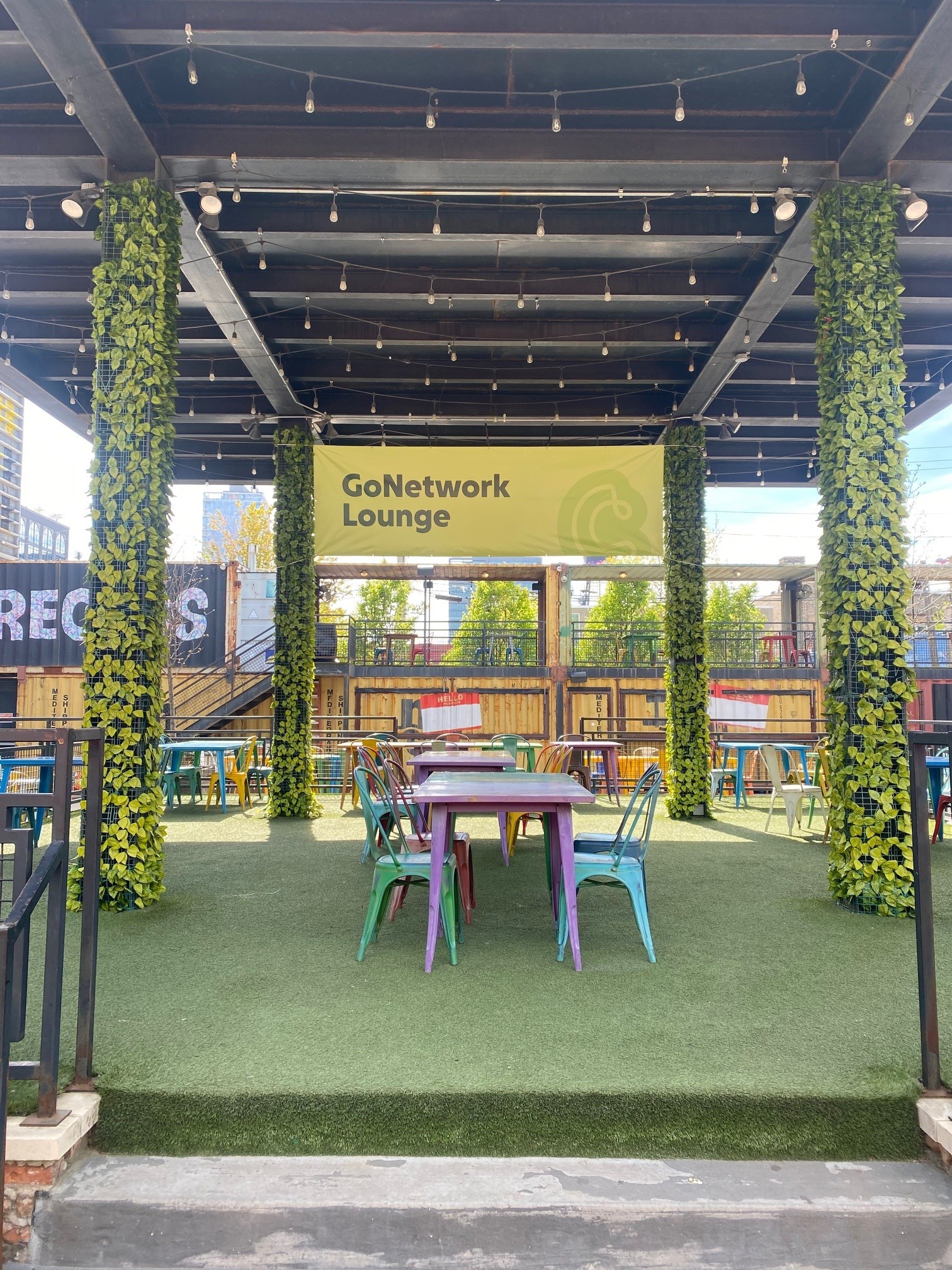 Hang banner for GoNetwork Lounge displayed in a vibrant outdoor seating area with greenery and colorful chairs.