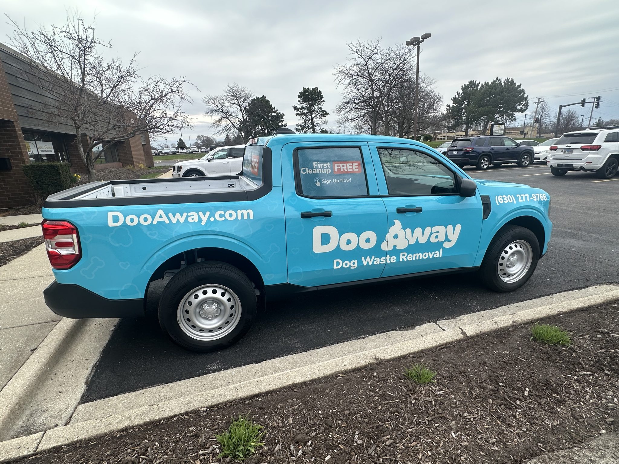 Partial truck wrap for Doo Away dog waste removal service featuring light blue background and bold white text.