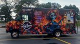 Full vehicle wrap for Antigua Mexican Grill featuring vibrant floral designs and a skeleton guitarist in a colorful mural.