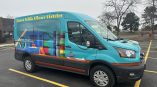 Full van wrap for Aurora Public Library District featuring colorful graphics and icons of library tools.