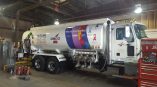 Full fuel truck wrap for OSCO featuring colorful cancer awareness ribbons and support messaging, displayed inside a garage.
