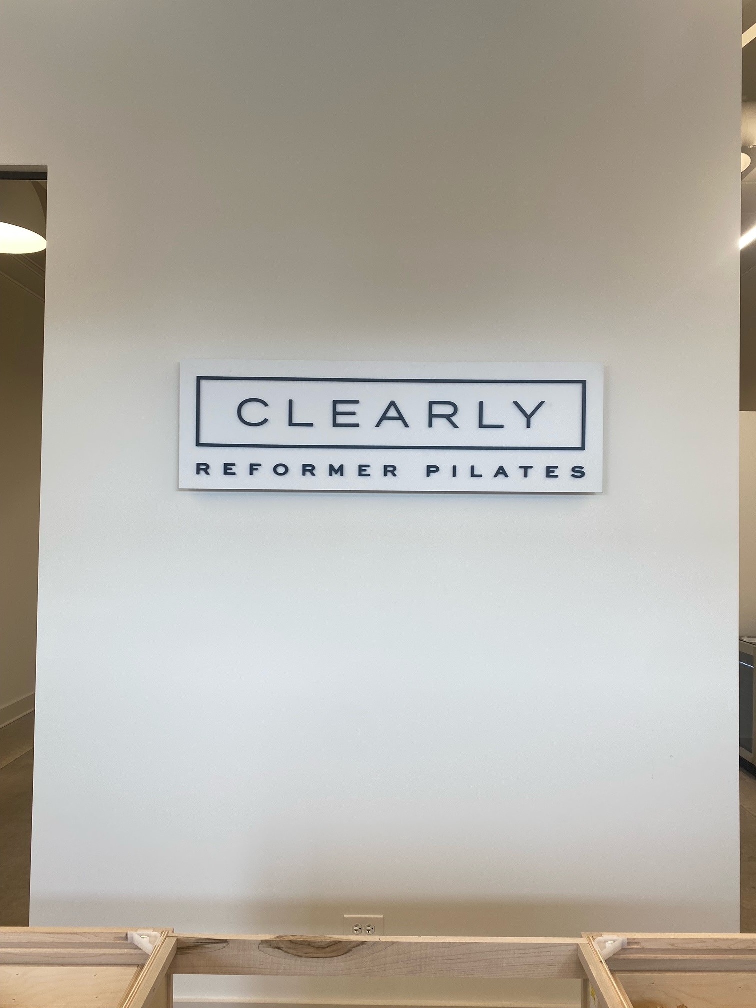 Dimensional acrylic sign for Clearly Reformer Pilates displayed on a plain wall.