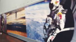 Wall mural of person flying with Red Bull suit and helmet above earth