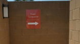 Trash Compactor direction signage on brown brick