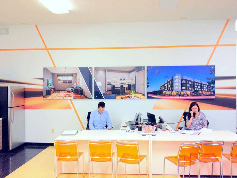Office with wall of graphics behind people sitting at a desk