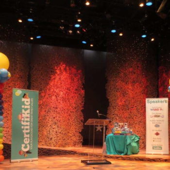 Certifikid retractable banner on a stage with balloons and a podium