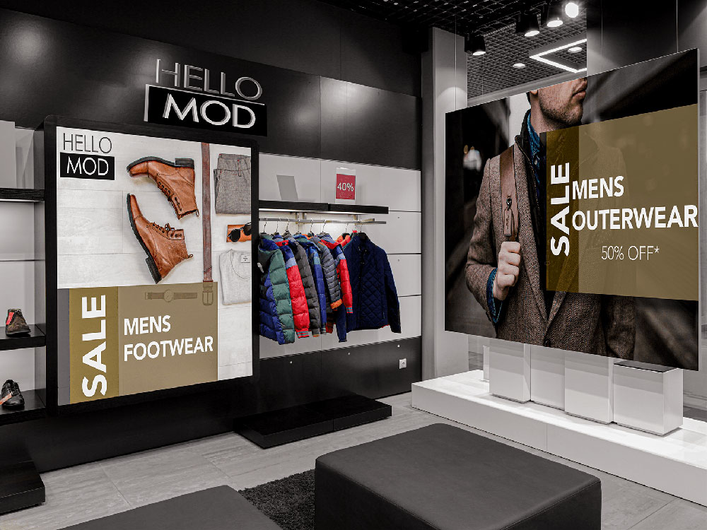 Men’s retail store with jackets hanging next to Hello Mod Mens Footwear & Outerwear signs. 